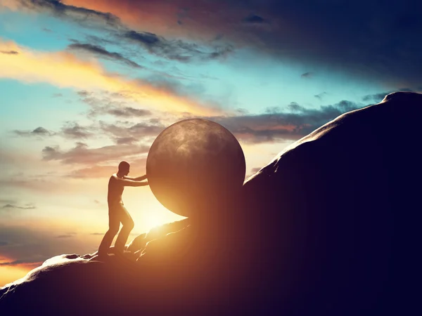 Man rolling huge ball up hill. — Stock Photo, Image