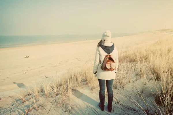 Женщина с ретро рюкзаком, смотрящая на море — стоковое фото