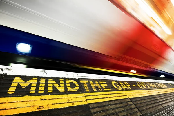 Mind the gap sign, train in motion. — 图库照片