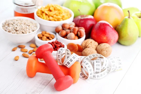 Mengukur pita dengan dumbbells dan buah-buahan untuk sarapan — Stok Foto