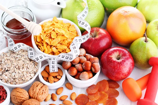 Measure tape with dumbbells and fruits for breakfast — Stock Photo, Image