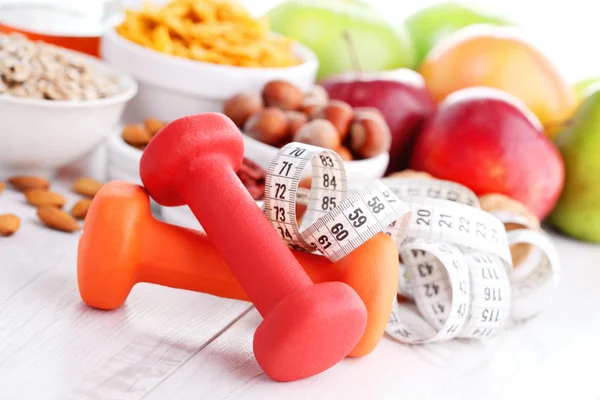 Measure tape with dumbbells and fruits for breakfast — Stock Photo, Image