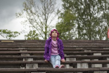 Üzgün küçük kız bankta oturuyor