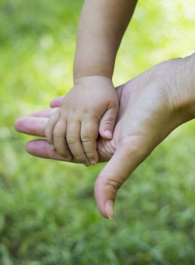 Anne oğul el yeşil çim bir arka plan üzerinde tutar..