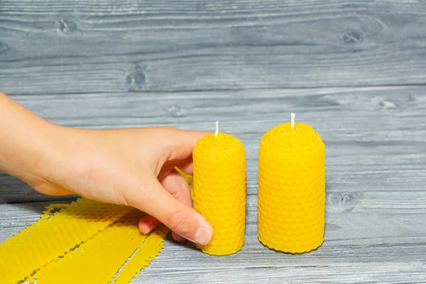 two beeswax candles on a wooden background.