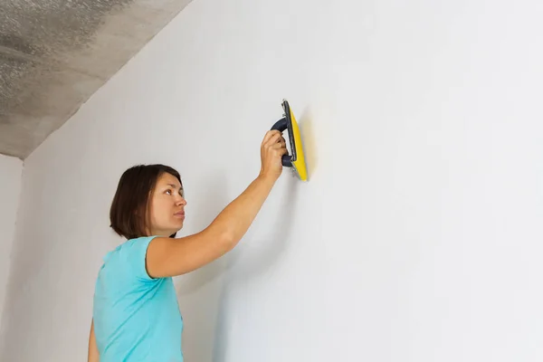 Kadın yeni evdeki duvarı hizaladı, daireyi onardı.. — Stok fotoğraf