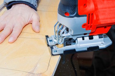 Genç marangoz elektrikli yapboz ve tahtayla çalışıyor..