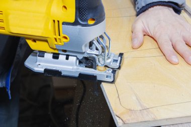 Genç marangoz elektrikli yapboz ve tahtayla çalışıyor..