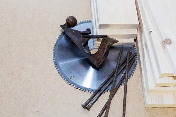 Light-colored wooden boards. Place for text, saw blade, plane, nails.