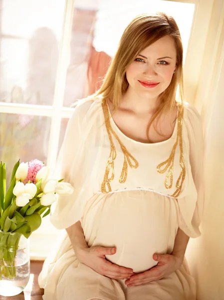 Kobieta w ciąży siedzi w pobliżu okna — Zdjęcie stockowe