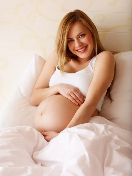 Gravid kvinna sitter på sängen — Stockfoto