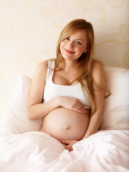 Gravid kvinna sitter på sängen — Stockfoto