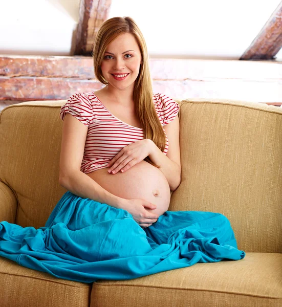 Zwangere vrouw zittend op de bank — Stockfoto