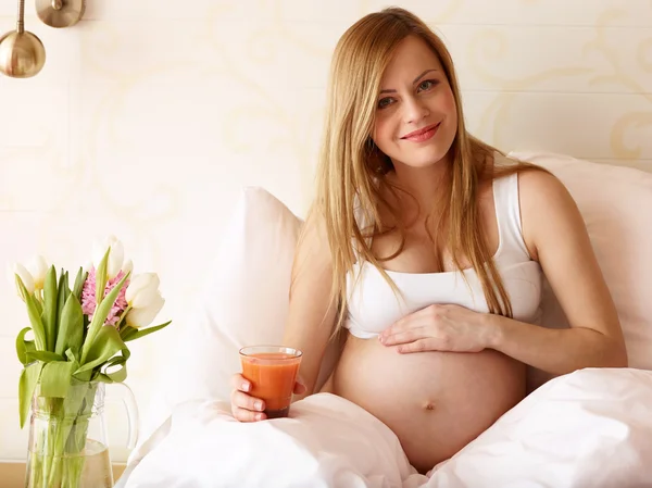 Schwangere mit Glas Saft Stockfoto