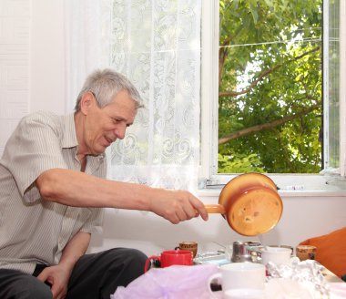 Mutfaktaki yaşlı adam arka planda.