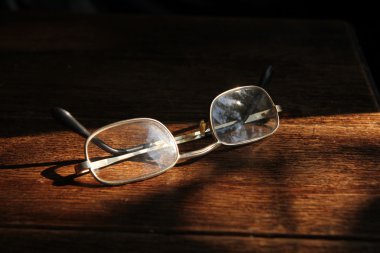 Gözlükleri ahşap masaya koy, kapat.