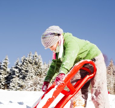 Kızaklı küçük kız. Dağda kızakla kaymak. Kış zamanı