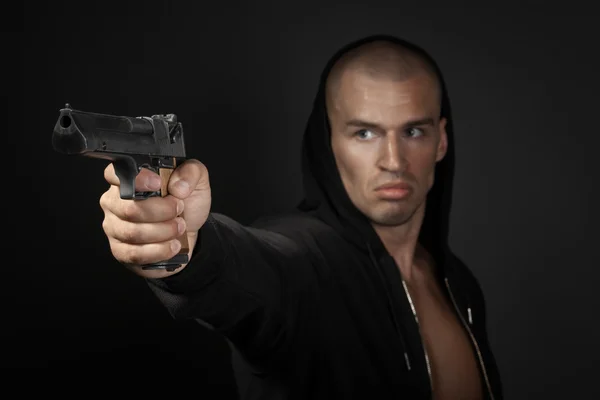 Homem disparando arma isolada em fundo cinza. foco na arma — Fotografia de Stock