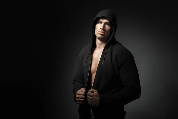 Hombre fuerte con sudadera con capucha aislado sobre fondo negro con copia — Foto de Stock
