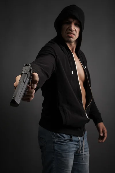 男は灰色の背景上に分離されて銃を撮影します。銃に焦点を当てる — ストック写真
