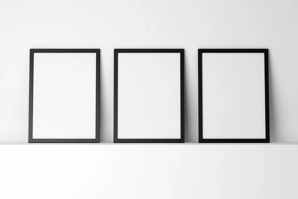 Three blank black photo frames on white shelf — Stock Photo, Image