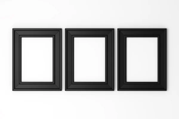 Three blank black photo frames on white wall — Stock Photo, Image