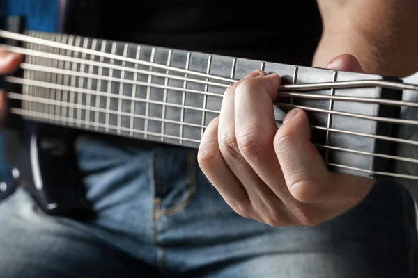Músico masculino tocando na guitarra baixo de seis cordas — Fotografia de Stock