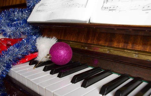 La gorra de Papá Noel y las decoraciones navideñas yacen en un piano . — Foto de Stock