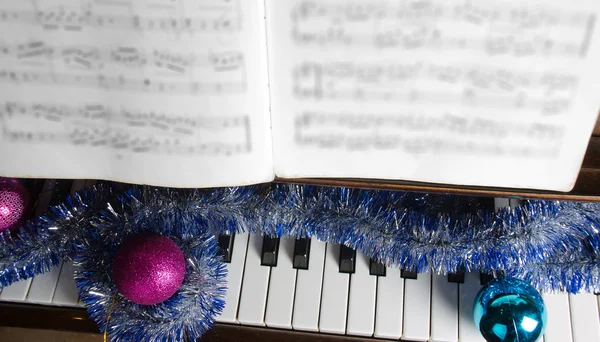 Los atributos de la celebración del Nuevo año y la Navidad se encuentran al piano — Foto de Stock