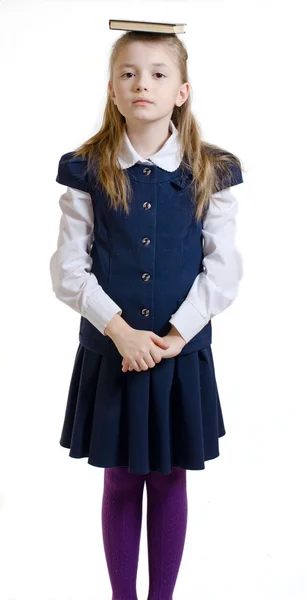 The girl keeps the book on the head in a school uniform — Stock Photo, Image