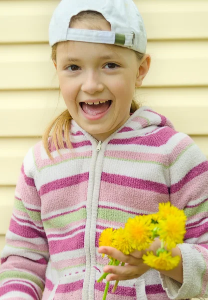 A menina faz uma grinalda de flores amarelas de um dente-de-leão — Fotografia de Stock