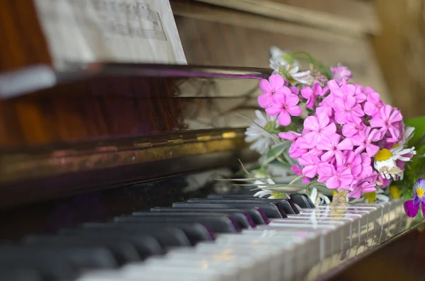 Bukett med sommarblommor på ett piano — Stockfoto
