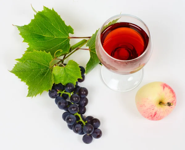 Кластер винограду і яблука лежать біля келиха вина з брендом — стокове фото