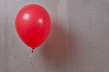 Gri texturies duvardaki kırmızı balon.
