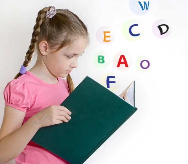 Meisje in een roze t-shirt lezen van een boek — Stockfoto