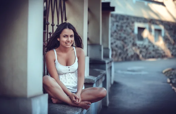 Brunette meisje zittend op straat — Stockfoto