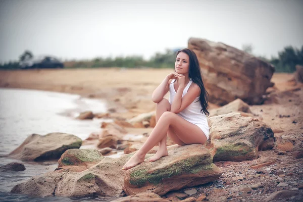 Vrouw op stenen in de buurt van de zee — Stockfoto