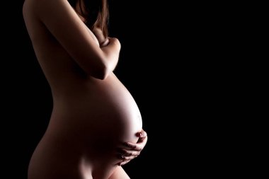 Siyah arka planda hamile bir kadın.