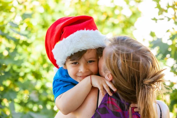 Noel Baba Şapkalı Neşeli Çocuk Annesinin Omzunda — Stok fotoğraf