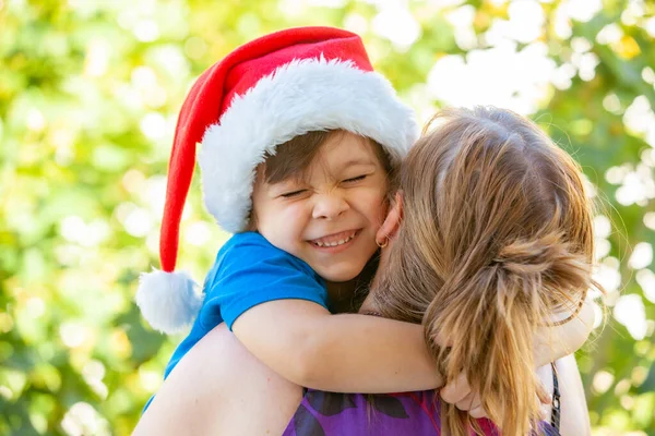 Noel Baba Şapkalı Neşeli Çocuk Annesinin Omzunda — Stok fotoğraf