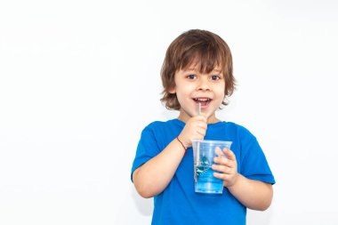 Hafif arka planda bir bardak su olan bir çocuğun portresi.