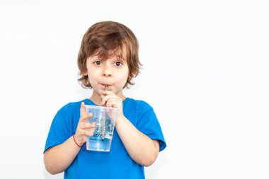 Hafif arka planda bir bardak su olan bir çocuğun portresi.