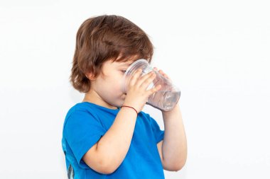 Hafif arka planda bir bardak su olan bir çocuğun portresi.