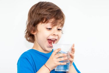 Hafif arka planda bir bardak su olan bir çocuğun portresi.