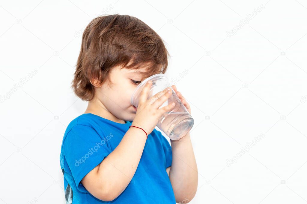 portrait of a boy with a glass of water on a light background