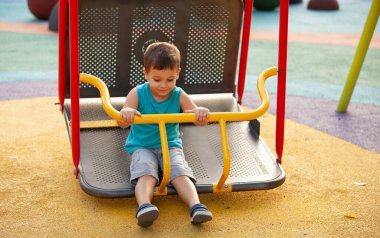 duygusal küçük çocuk parkta sallanıyor.