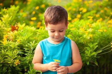 Parkta çiçekli küçük bir çocuk