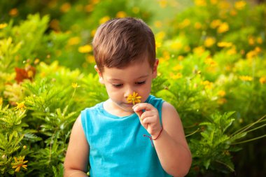 Parkta çiçekli küçük bir çocuk