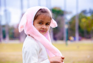 Parkta pembe tavşan şapkalı mutlu kız.