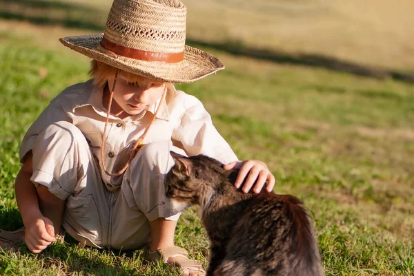 一个戴帽子的小男孩 公园里有一只猫 — 图库照片